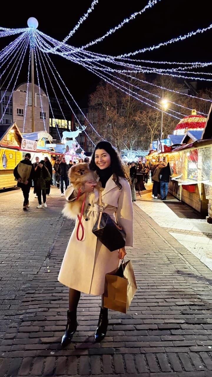 Éleveuse tenant un chiot Spitz Allemand nain en laisse lors d’un marché nocturne animé.
